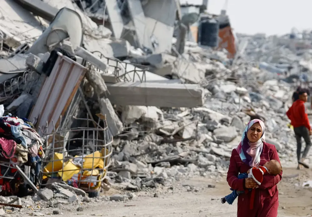 una-mujer-palestina-carga-su-bebe-entre-los-escombros-foto-reutersmahmoud-issa-7IYA3TI53MVJNPXNQT3FMAK2KU